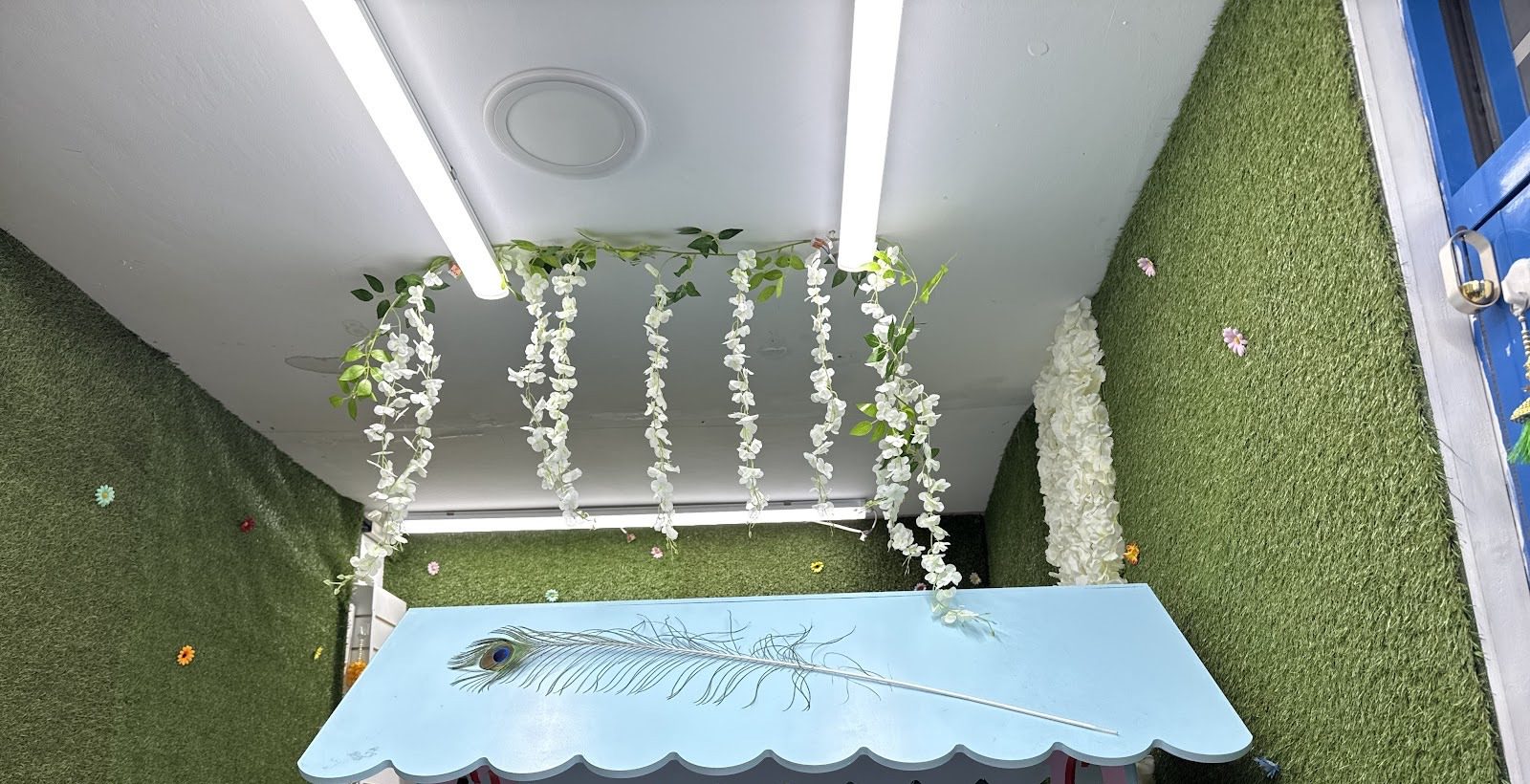 The room inside PANIPURIWALA, with green walls, hanging blossom and the painted stall