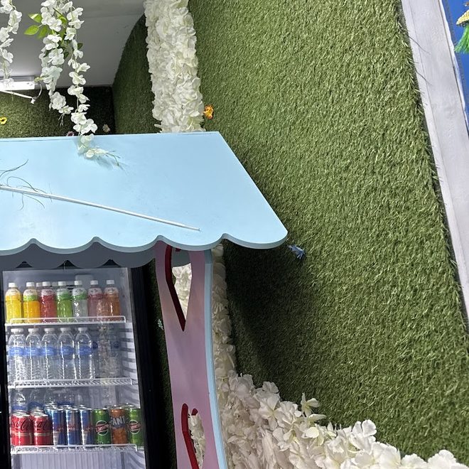 The drinks fridge beside the stall, with blossom on the wall