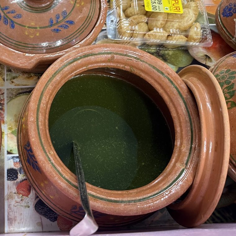 A clay matka of green flavoured pani on the counter